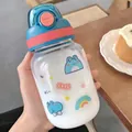 Detail shot of a cute glass water bottle featuring cartoon stickers and a bounce lid - 400ml / Blue