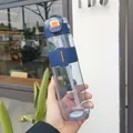 Blue plastic sports water bottle with straw and flip-top lid being held outdoors. - 390-760ML / Blue