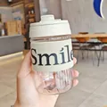 Close-up of portable plastic coffee cup with 'Smile' canvas sleeve and dual-drink lid - 500ml / White