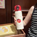 Nahaufnahme einer Person mit einer niedlichen, cremefarbenen Isolierflasche mit Katzenmotiv - 500ml / Apfelkatze-Stil (YSM8651)