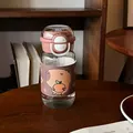 Süße Capybara-Cartoon-Wasserflasche mit brauner Lederhülle auf einem dunklen Holztisch - Capybara (1011) / 450ml