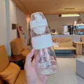 Detailansicht einer klaren Sportwasserflasche mit weißem Klappdeckel in der Hand gehalten - 720ml / Weiß