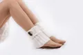 Detail shot of white knitted leg warmers with brown buttons and cable knit texture - One Size / White