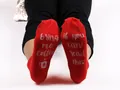 Detailed view of red cotton socks with funny 'bring me coffee' text on the soles - Red