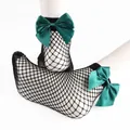 Detail view of black fishnet ankle socks featuring large emerald green satin bows - One Size / Green