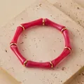 Vista de detalle de una pulsera de acrílico rosa con segmentos de bambú y anillos dorados - Rosa intenso