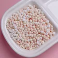 Close-up van 4mm gematteerde macaron glaskralen in een wit bakje voor DIY hobby's - 200 Stuks / 03 (ai-Roze Oranje)
