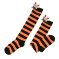 Close-up detail of plush reindeer doll and green bow on orange and black striped socks - Kids (7-12 Years) / Orange Black Stripes / Bow Reindeer