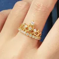 Vue macro détaillée d'une élégante bague couronne en or avec zircons 5A sur un doigt - Taille 5 / Bague Couronne Princesse-K Jaune