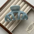 Detailed macro view of a light blue marble textured hair claw clip in a wooden box - Jelly Blue