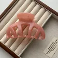 Close-up view of a pink pumpkin hair claw clip in a luxury wooden jewelry display case - Jelly Pink