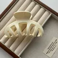 Detailed macro view of cream-colored bone-shaped hair claw clip on wooden jewelry box - White