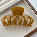 Detail view of an amber-colored resin hair claw clip in a jewelry tray, smooth texture - PC Material / Jelly Yellow