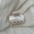 Detail of elegant marble pattern hair claw clip on soft linen fabric background. - S / White