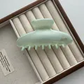 Gedetailleerde close-up van een grote mintgroene haarklem van 13 cm op een vintage sieradentray - Ingot Stijl / Groen