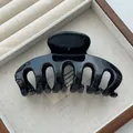 Close-up of a glossy black Korean-style shark hair claw clip in a display tray - PS Material / Black