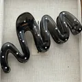 Close-up of a black translucent wavy hair claw clip with white polka dots - Snake Style / 13cm / Black White Polka Dot