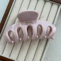 Detail showing a glossy light pink dragon bone hair claw clip in a jewelry box - With Label / Pink