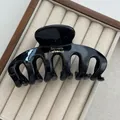 Close-up view of a glossy black hair claw clip with gold Barrette La France text detail - With Label / Black