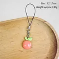 Cute pink peach resin phone charm featuring green leaves and a black lanyard strap - Berries