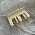 Detailopname van een minimalistische crèmekleurige haarklem op gekreukt papier - Beige