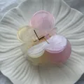 Close-up of gradient pink and yellow plumeria flower hair claw clip with gold spring detail. - Smudged Butterfly