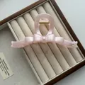 Detailopname van een 13 cm roze parelmoer haarklem met strik op een fluwelen juwelendoos. - Vlinderdas Stijl / Roze