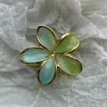 Dettaglio macro di una pinza per capelli a fiore di frangipane verde con eleganti bordi d'oro - Plumeria Verde Lime con Bordo Dorato