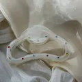 Detail of a cream marble hair claw clip with colorful rhinestone accents on silk fabric. - Semicircle