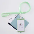 Mint green cartoon lanyard ID card holder with a cute stick figure illustration - Pinch Face