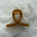 Detail view of a translucent amber jelly hair claw clip on white textured background - Jelly Dark Coffee