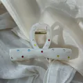 Macro detail of marbled texture and colorful rhinestones on a white bow hair claw clip - 11cm Bowknot