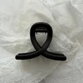 Close-up view of a minimalist matte black hair claw clip on white textured paper - Matte Black