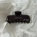 Close-up van een glanzende donkerbruine grote haarklem met Hand Made tekstopdruk - L / Roodbruin
