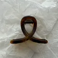Detailed view of a minimalist amber tortoiseshell hair claw clip with a loop design. - Matte Amber