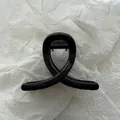 Detailed close-up of a minimalist black claw hair clip on a textured white background - Bright Black