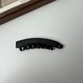 Gedetailleerde macro-opname van een glanzende zwarte bananenhaarklem met interne tanden. - 10cm Grootte / Lichtzwart