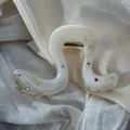 Detail shot of creamy white hair claw clip with colorful rhinestone accents on fabric - Geometric Hollow