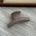 Detailed close-up view of a small jelly grey arched hair claw clip on textured background - Dark Milk Tea