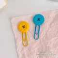 Set of cute yellow and blue button-shaped paper clips displayed on pink wrinkled paper - Yellow Button + Blue Button