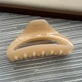 Close-up of a minimalist beige resin shark hair claw clip on textured background - Fruit Yellow