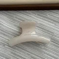 Close-up detail of a small cream-colored curved hair claw clip with a glossy finish - Fruit White