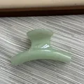 Macro view of a small jelly green curved hair claw clip on textured background - Fruit Green