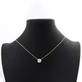 Close-up of a minimalist 14k gold-filled necklace with a round moissanite pendant on a mannequin. - 1 Carat Eight-Prong Style / Gold