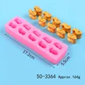 Nahaufnahme einer rosa Silikonform mit Maßen und goldenen Gipsnuggets zur Dekoration - 10-Loch Barren Schokoladenform (50-3364-A) / Rosa / 17.2x5.5cm