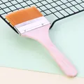 Close-up of a nylon pastry brush with a wooden handle resting on a metal cooling rack. - Size 11