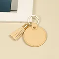 Porte-clés minimaliste circulaire en cuir beige avec un élégant détail de pompon doré - Glands ronds / Orange Rond Gland