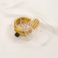 Detailed view of high-quality golden metallic thread spool in a clear storage box - 3 Strands 0.2mm 100m / 18K Gold