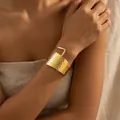 Detalle en primer plano de un brazalete dorado martillado estilo vintage en una muñeca - Brazalete Abierto con Textura Martillada Ancha (DTZ85) / Dorado