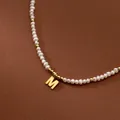 Macro detail shot of a vintage freshwater rice pearl necklace with gold M initial pendant - M